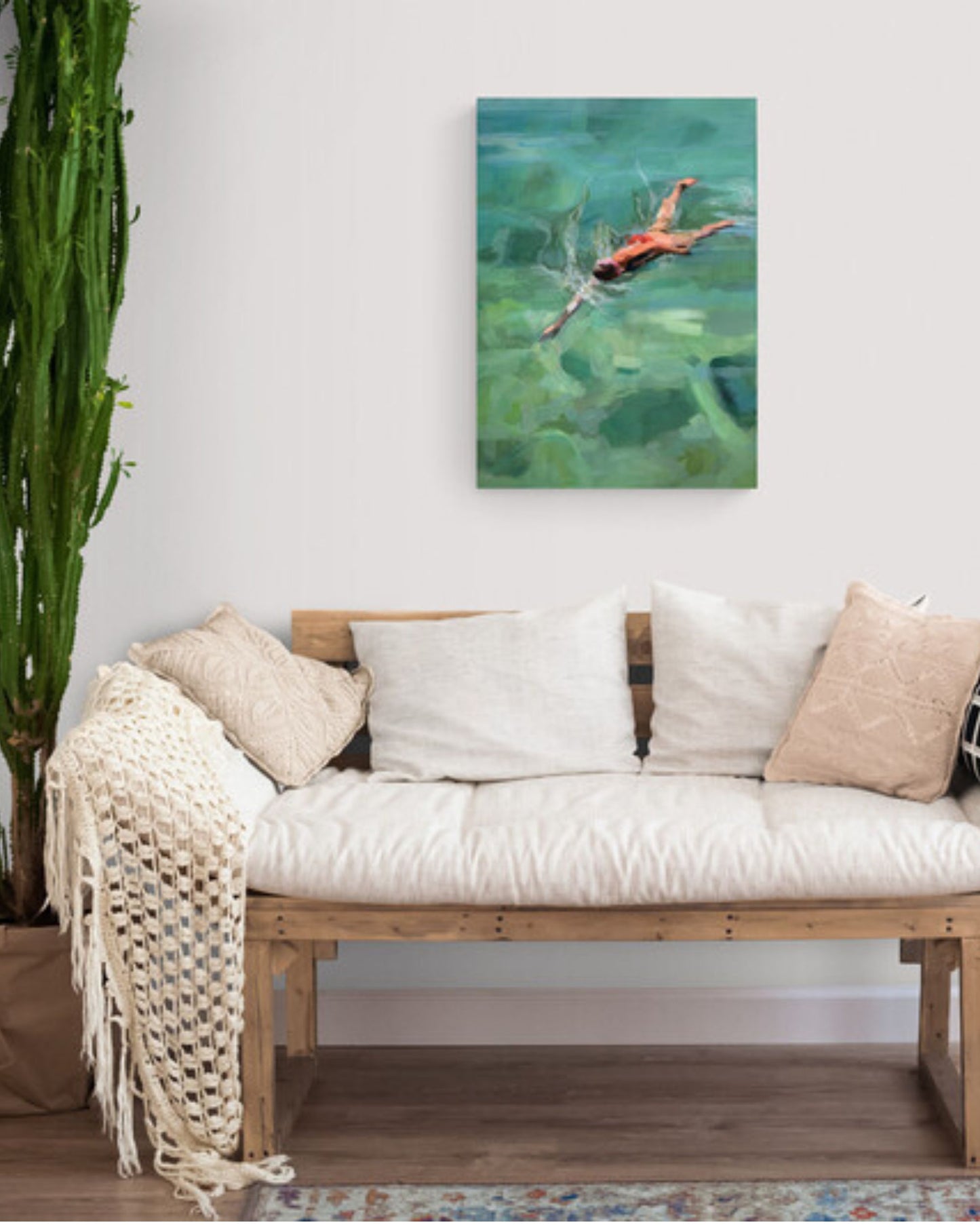 Living room with a wooden bench, white cushions, and an original painting of a woman swimming in green water.